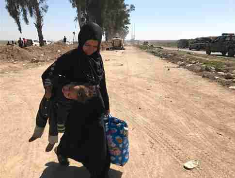 Woman fleeing Mosul carries her child in one hand and a bag of belongings in the other (CNN)