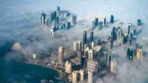 An aerial view of Doha, Qatar, in the fog, as the sun rises