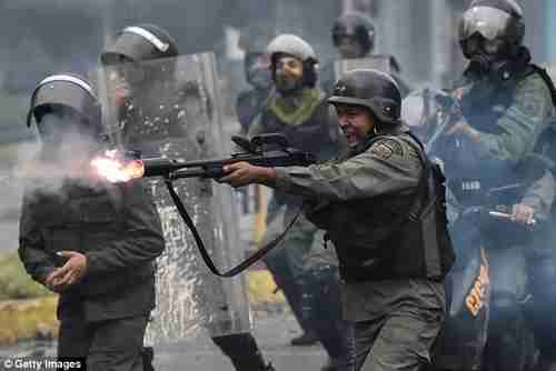  A member of the national guard fires his shotgun during clashes in Caracas, Venezuela, in July (Getty)