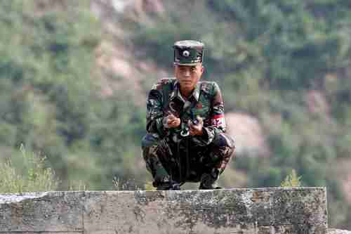 A North Korean soldier squats along the Yalu River in Sinuiju, North Korea, which borders Dandong in China's Liaoning province, Sept 9, 2017.
