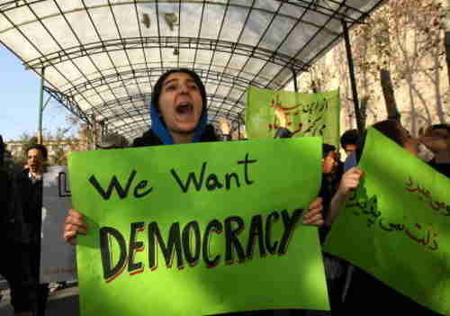 Protester in Tehran, Iran, on Monday with banner, 'We Want Democracy!' (Getty)