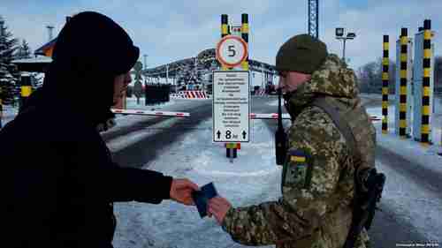 Ukrainian border guards prevent Russian men, aged 16-60, from entering Ukraine. Sign says: 'Do not stop between the striped columns.' (RFE/RL)
