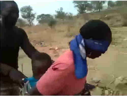 Screen shot from video shows soldier pushing blindfolded woman with baby to the ground, just before he shoots both of them dead.